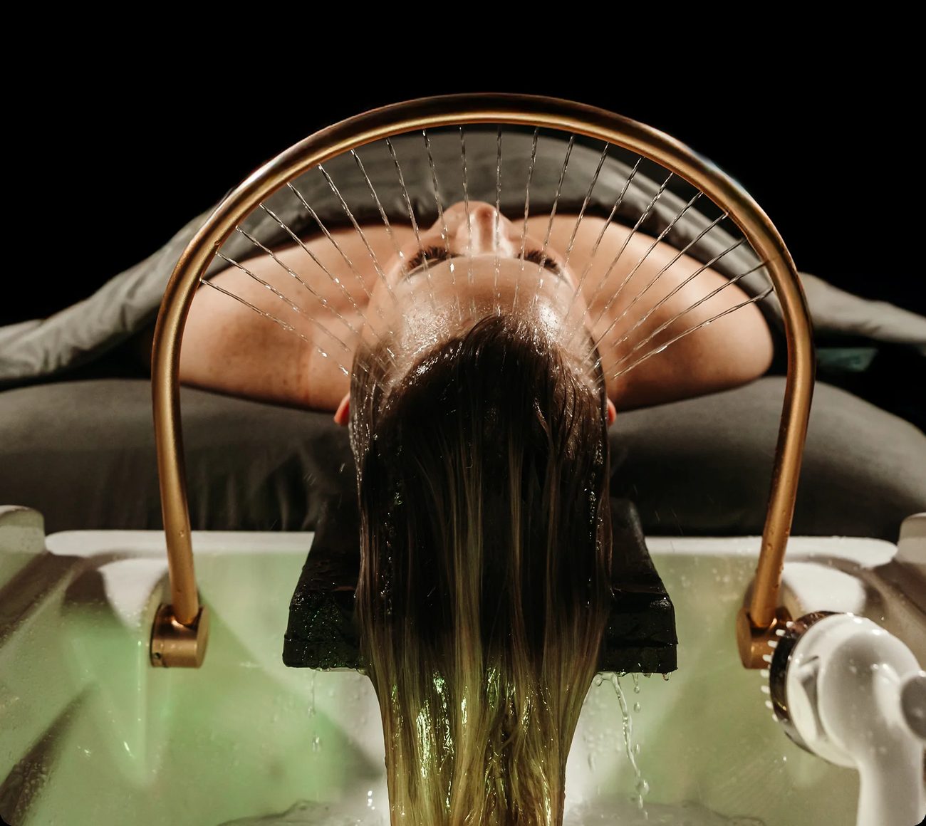 A guest lying back beneath the copper head spa halo as water fans over the scalp